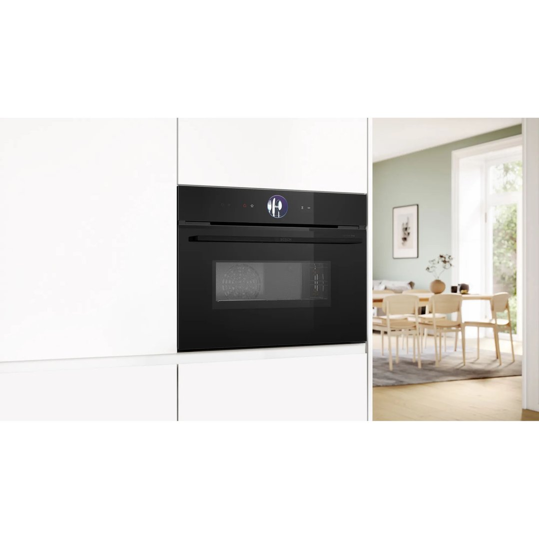 Black combination oven with microwave built into white cabinetry in a kitchen