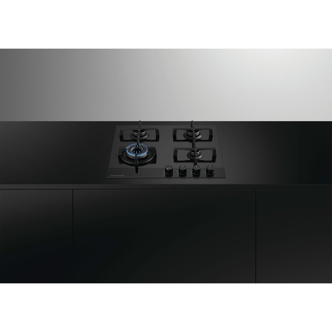 Black gas on glass cooktop with four burners, one lit, in a modern kitchen