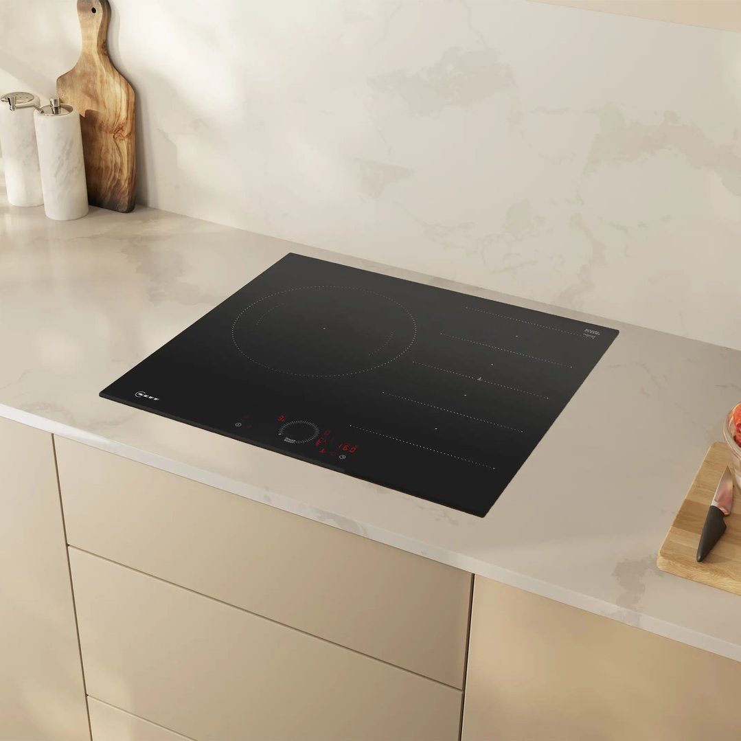 Black induction cooktop built into a light-colored kitchen countertop with accessories