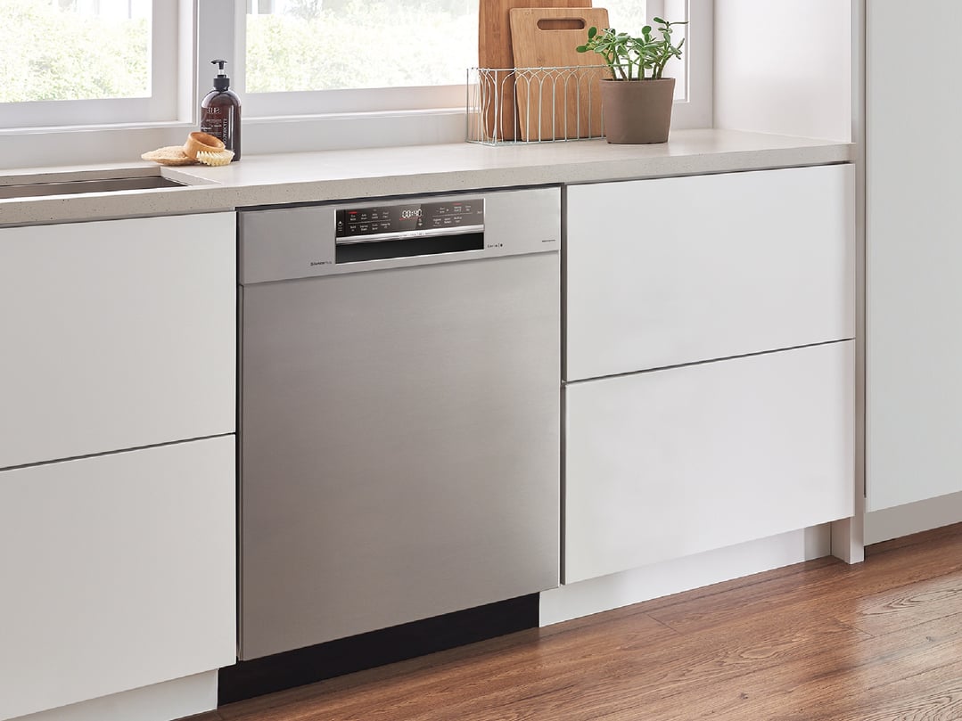 Built-under dishwasher in a modern kitchen with white cabinets and wooden floor