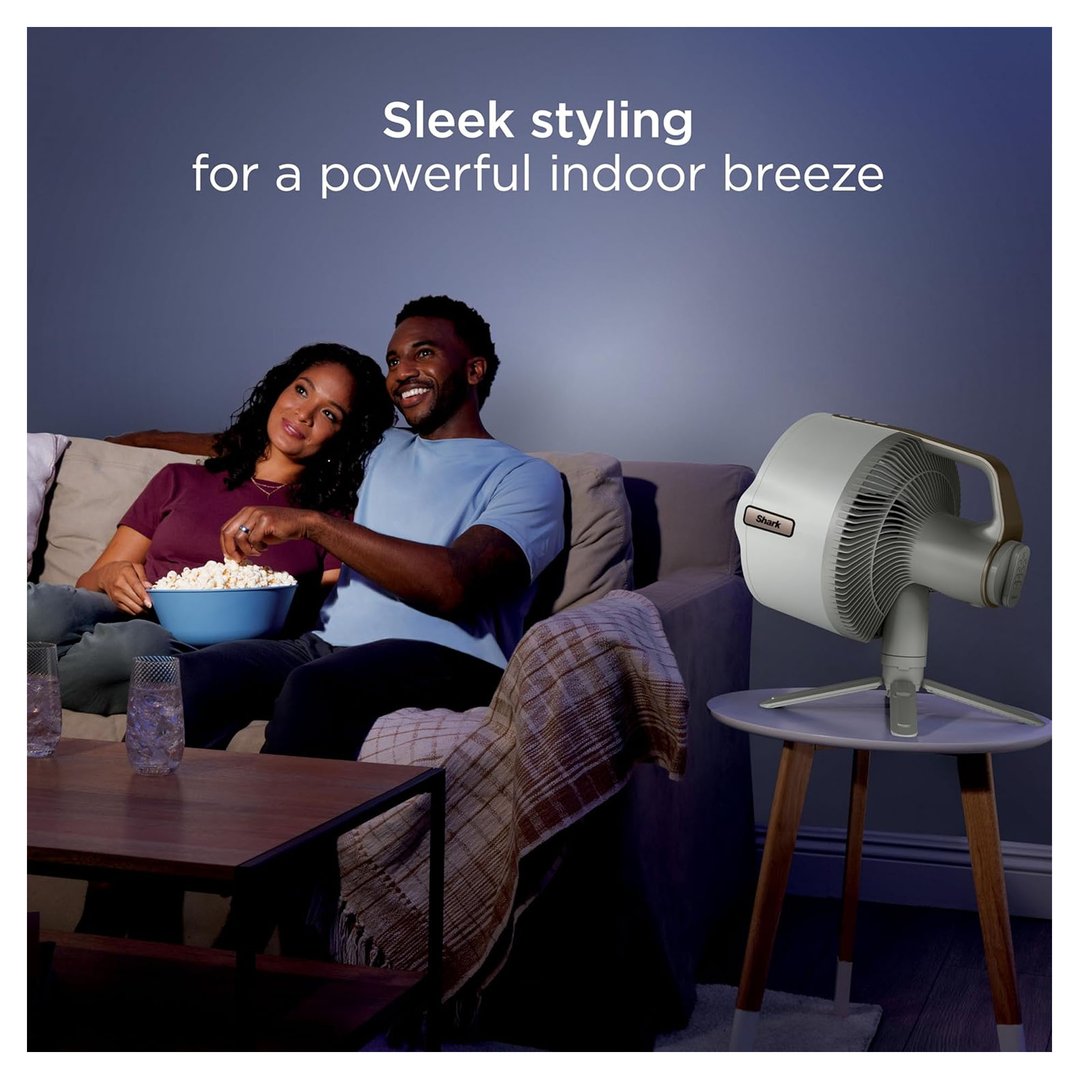 Couple watching TV on a sofa with a Shark FlexBreeze fan on a side table