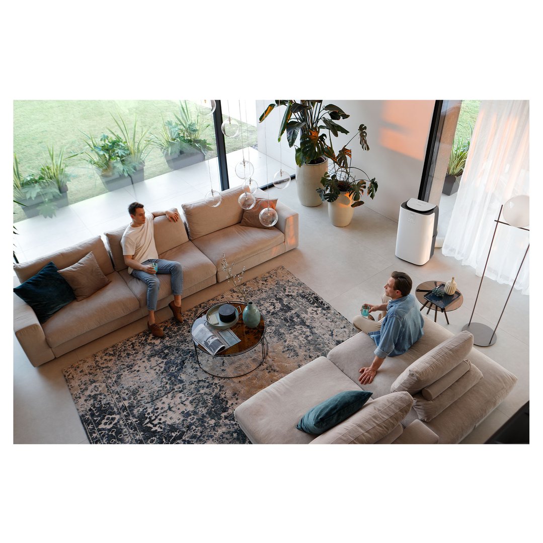 Two men relaxing on sofas in a modern living room with an air conditioner