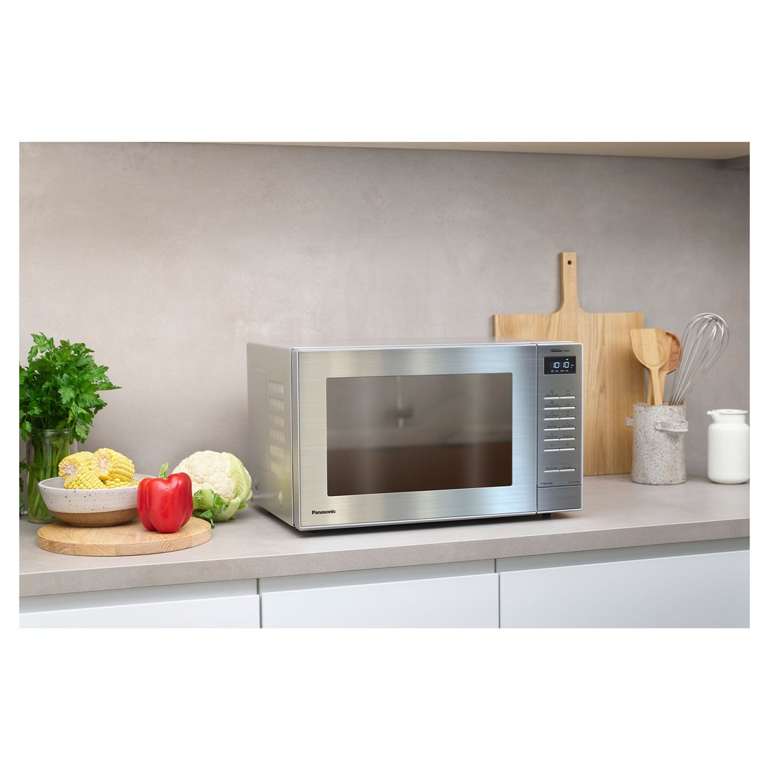 Panasonic microwave on a kitchen counter with vegetables and utensils