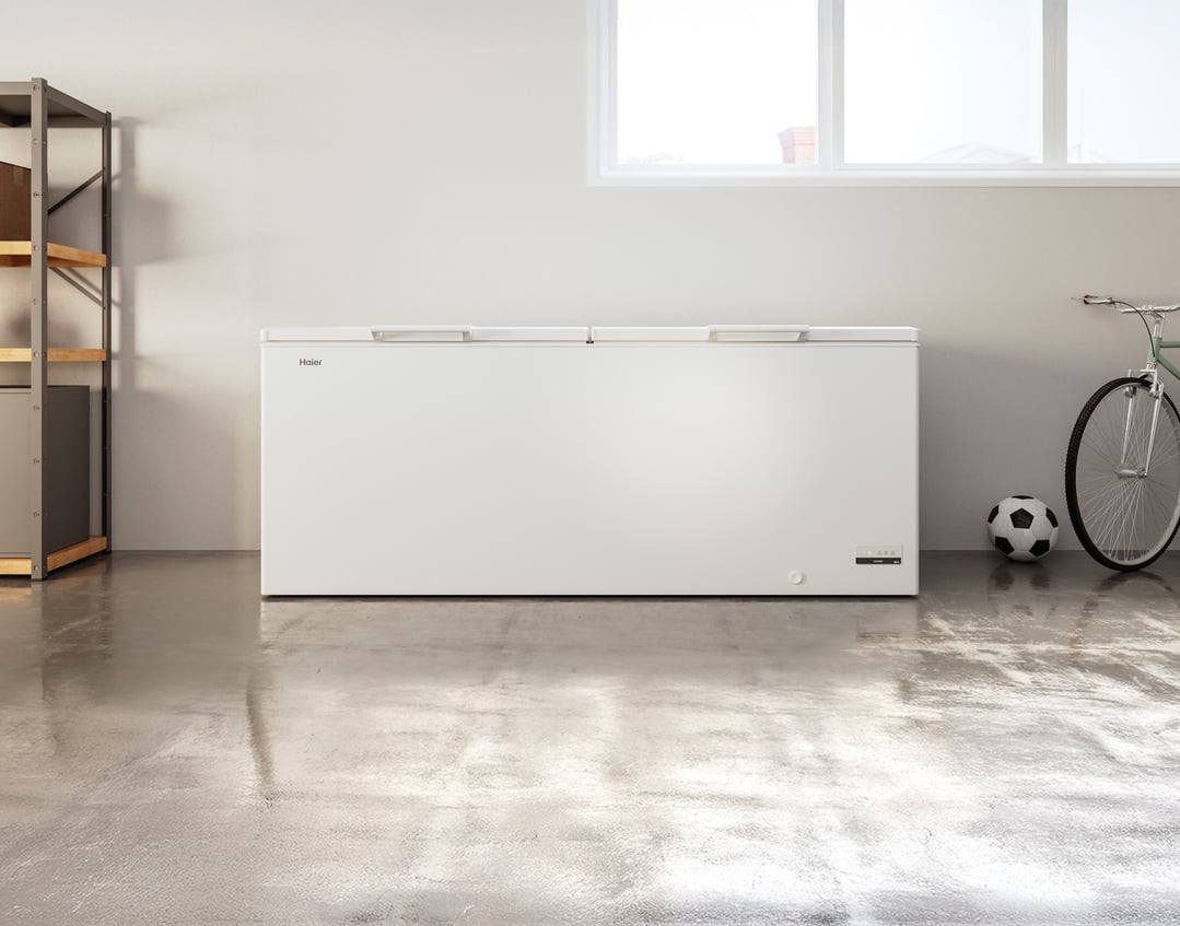 A white Haier chest freezer in a garage with a bicycle and soccer ball
