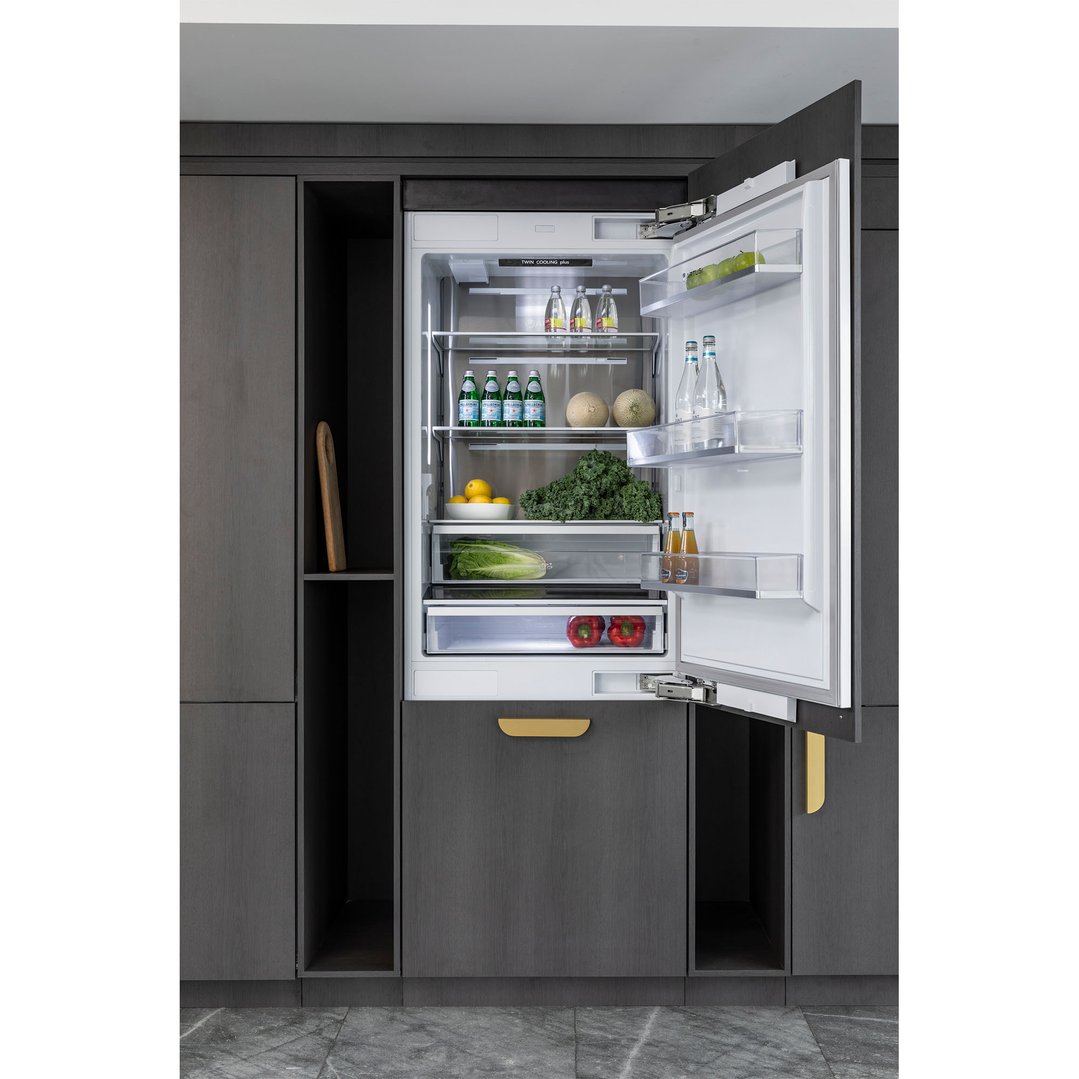 Integrated bottom mount fridge with door open in a dark wood kitchen