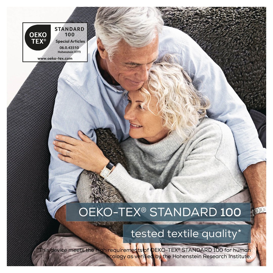 Elderly couple embracing on a sofa, with a heating pad visible