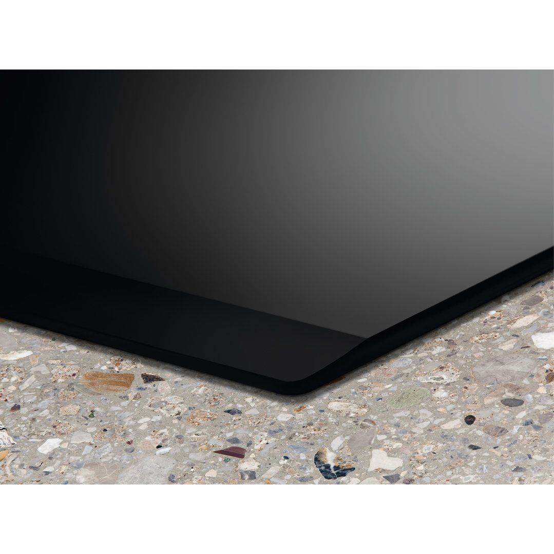 Close-up of a black induction cooktop installed in a speckled grey countertop