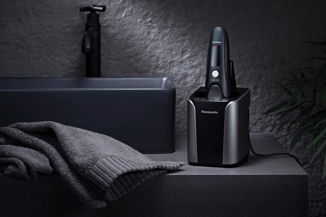 Panasonic shaver and charging dock on a bathroom counter with a dark sink