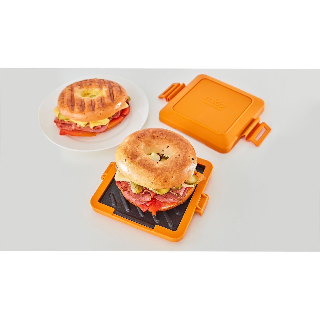 Two bagels with fillings, one on a plate and one in a sandwich maker