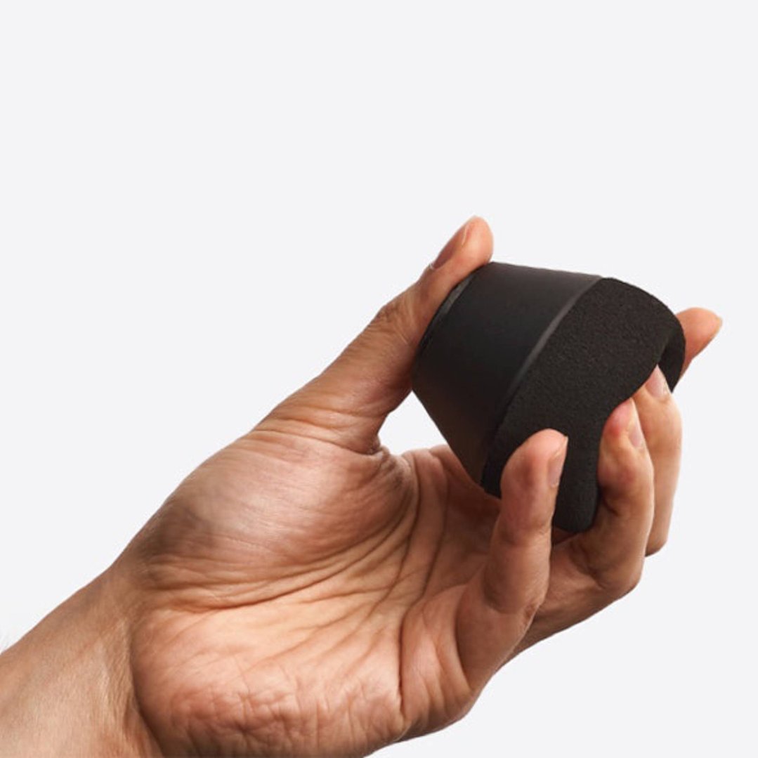 Hand holding a black Supersoft™ fitness accessory against a white background