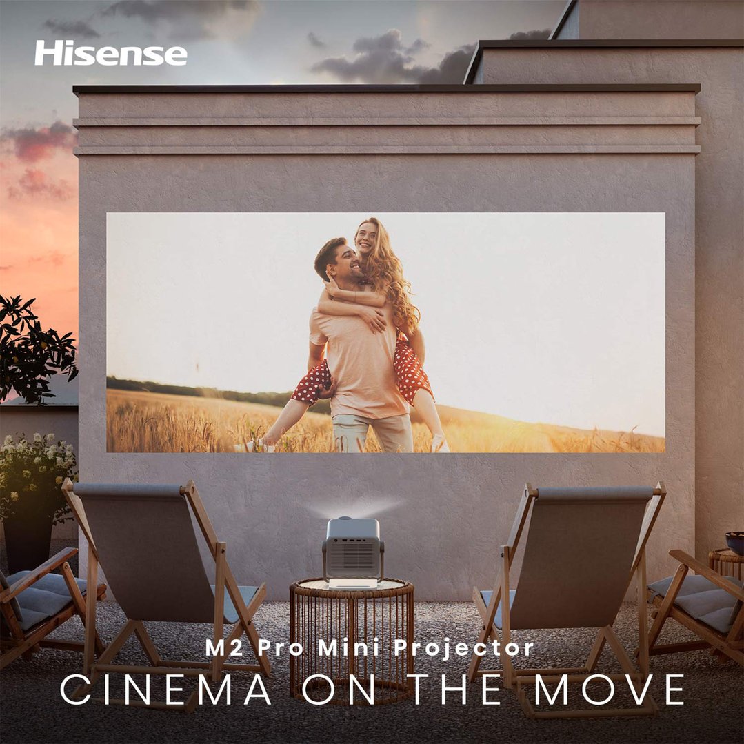 Projector displaying a movie scene on an outdoor wall with two chairs