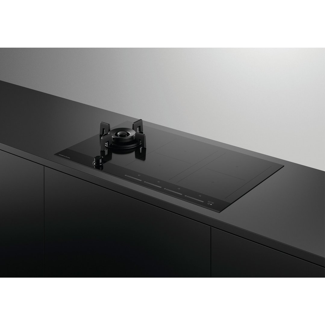 A black hybrid cooktop with one gas burner and four induction zones in a modern kitchen