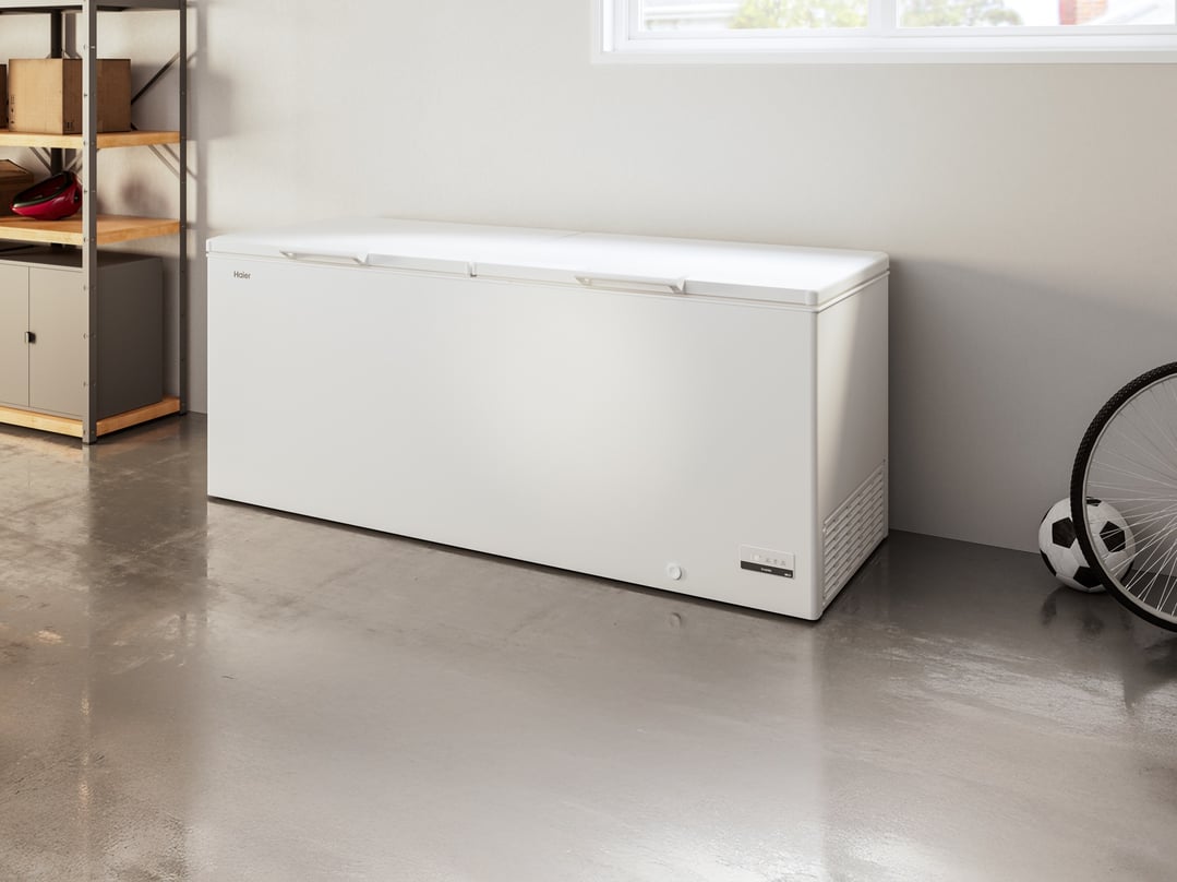 White Haier chest freezer in a garage with shelving, a bicycle, and a soccer ball