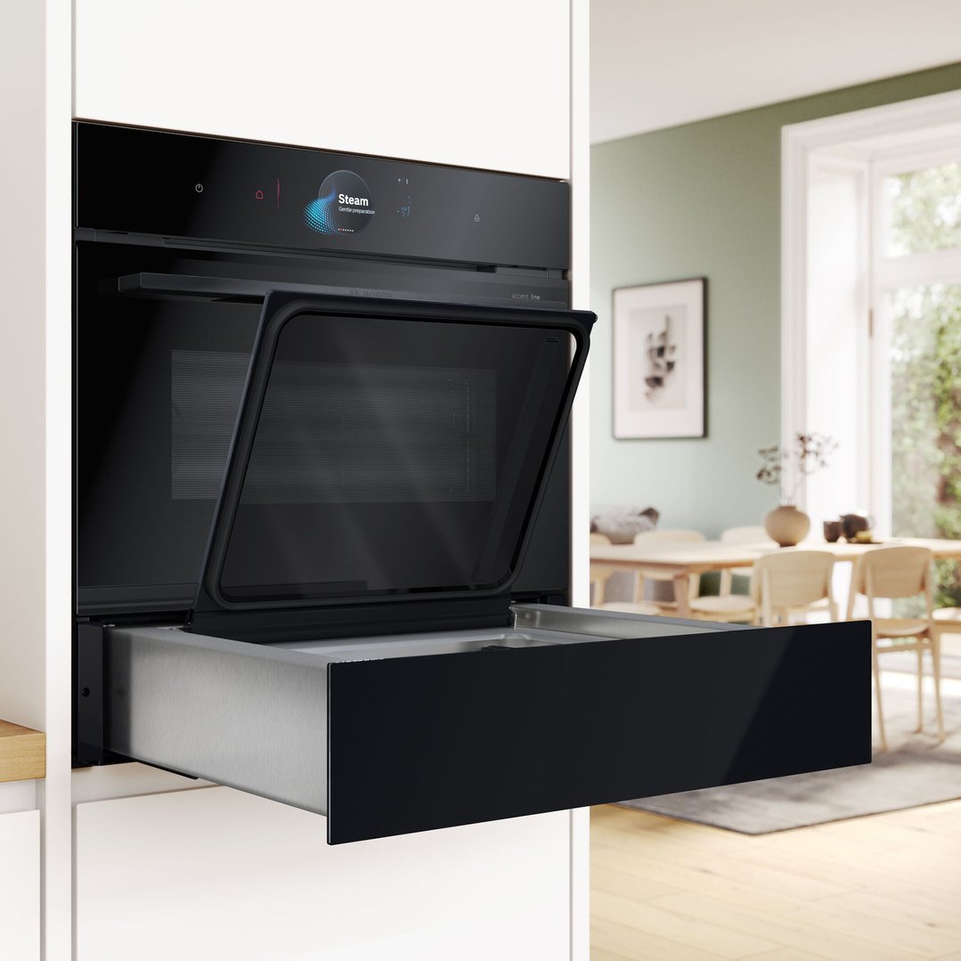 Black built-in oven with open door and vacuum drawer in a modern kitchen