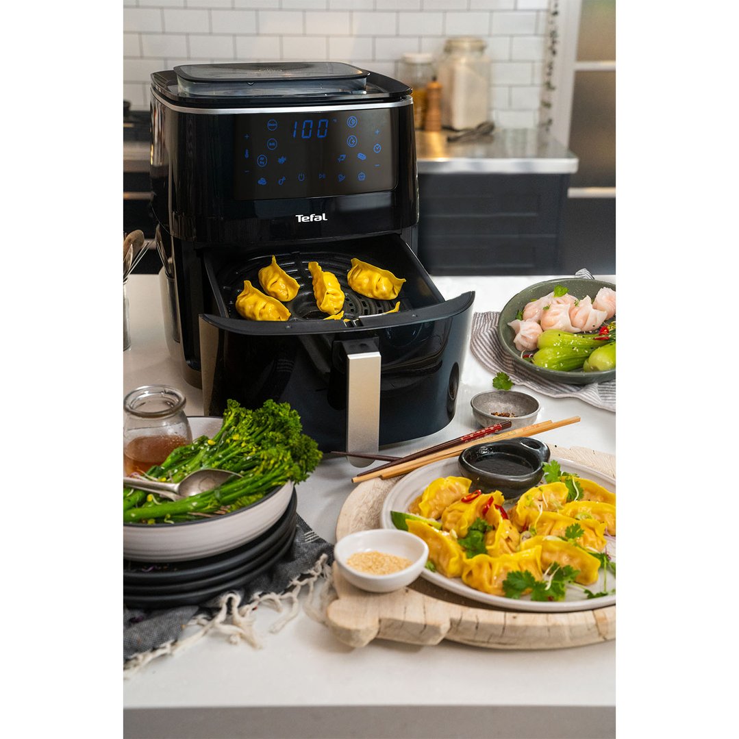 Black Tefal Easy Fry Grill & Steam XXL Air Fryer cooking dumplings in a kitchen