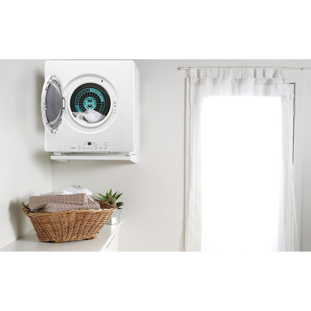 White dryer with open door and laundry inside, above a basket of towels
