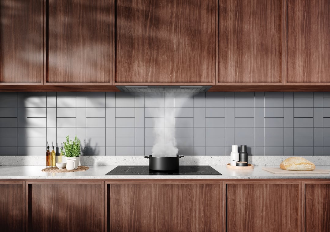 An integrated rangehood above a cooktop with a pot steaming in a modern kitchen