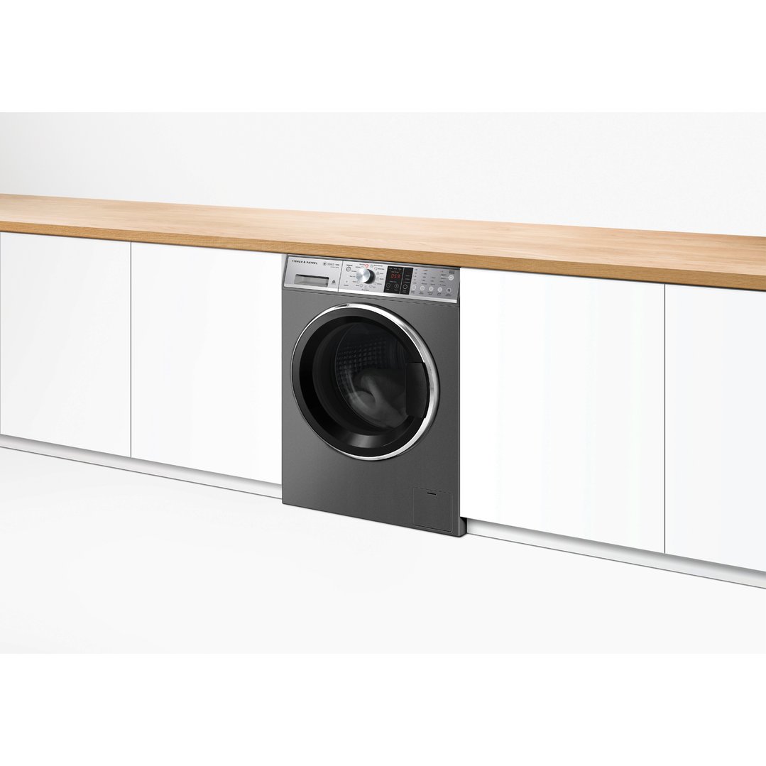 Front load washing machine integrated into white cabinetry with a wooden countertop