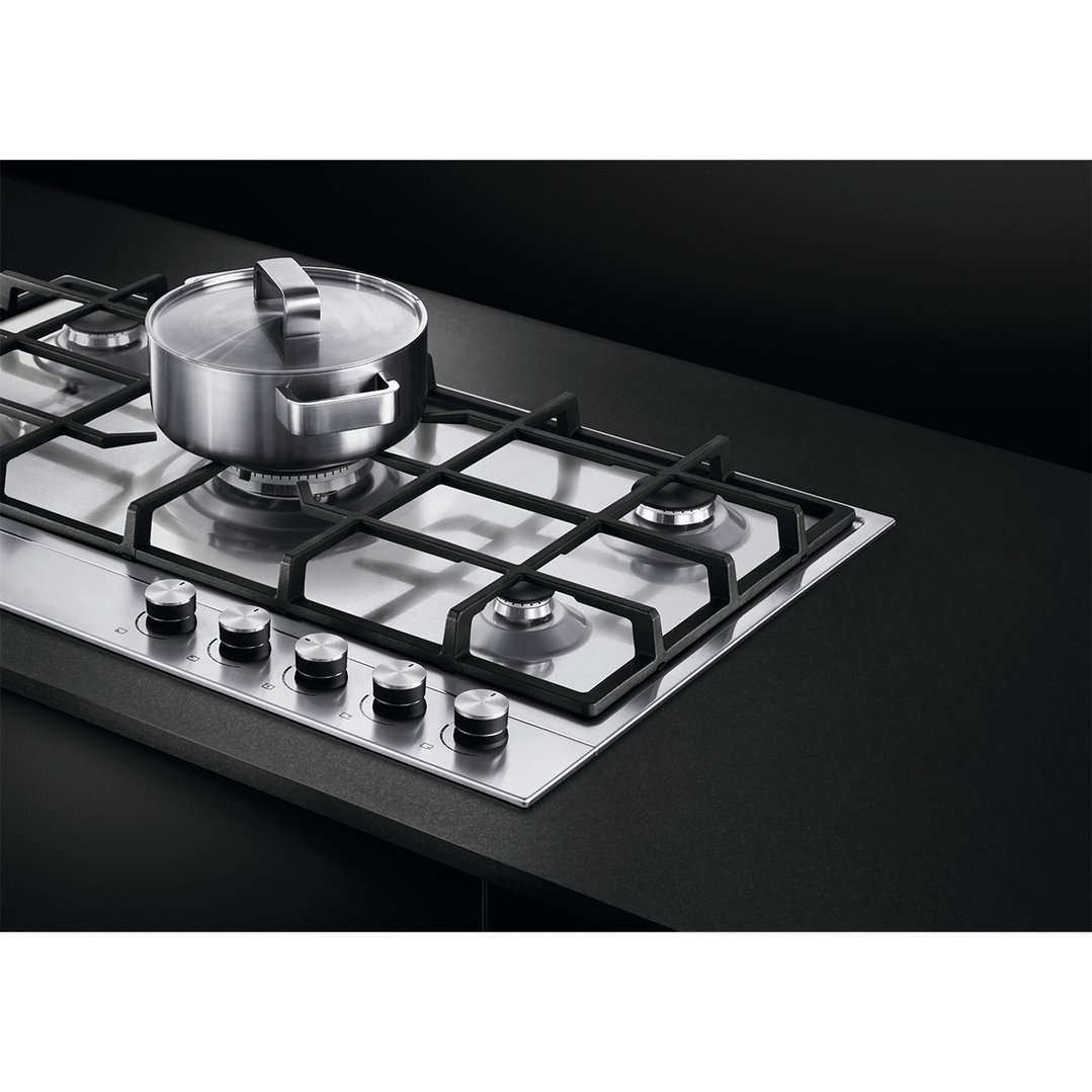 Stainless steel 5 burner gas cooktop with a pot on a black countertop