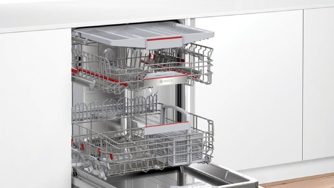 Open Bosch dishwasher with racks pulled out in a white kitchen