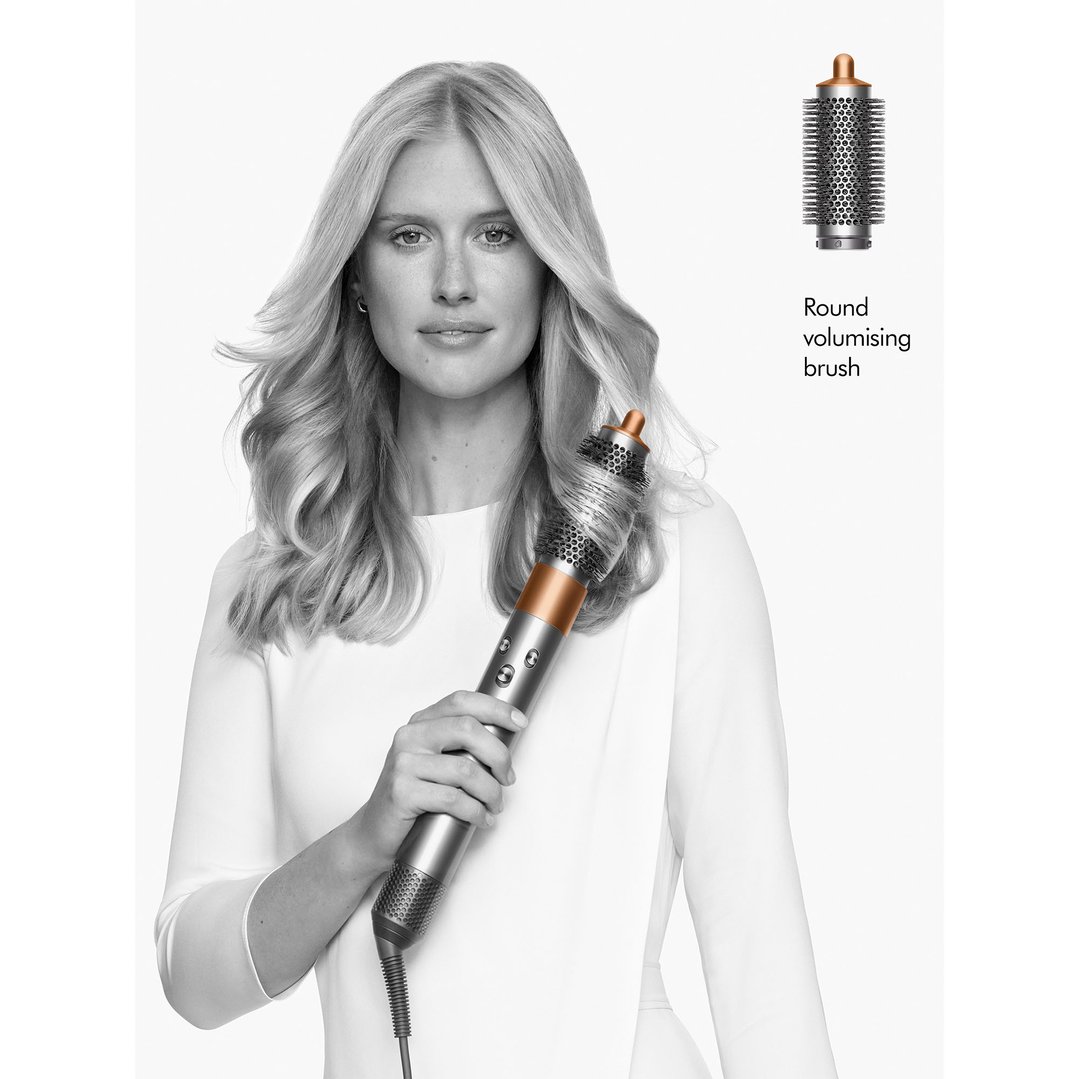 Woman holding a Dyson Airwrap multi-styler with a round volumising brush attachment