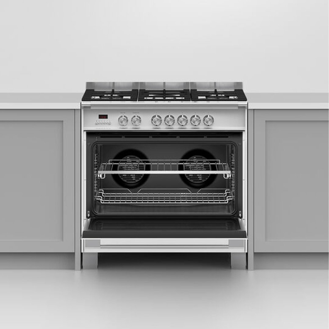 Freestanding dual fuel cooker with oven door open in a kitchen setting