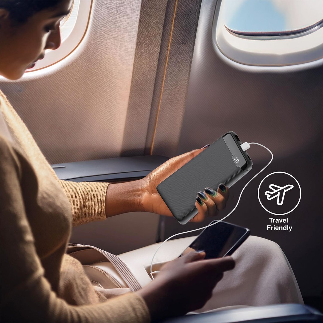Person holding a power bank and a phone while sitting on an airplane