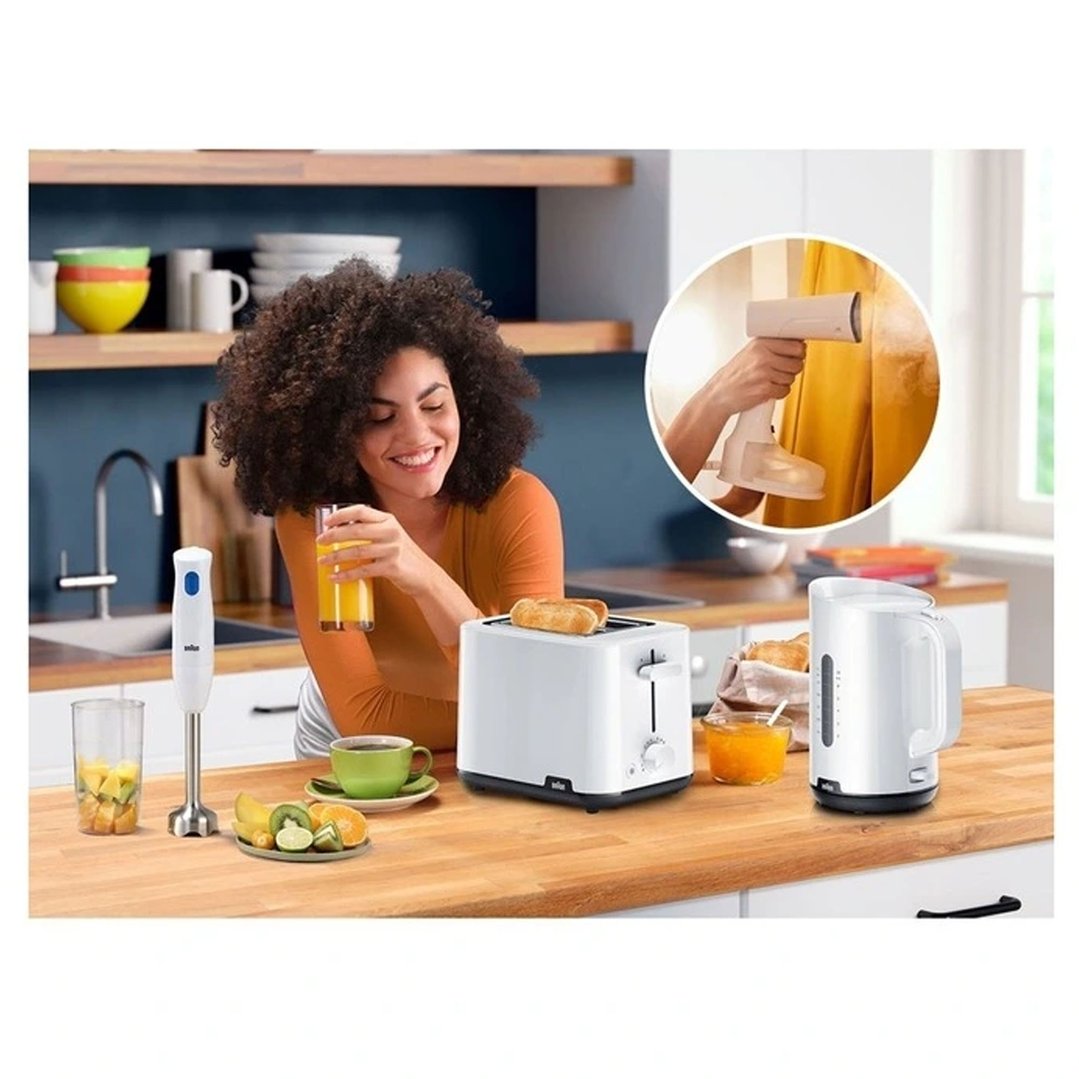 Woman holding juice, with a toaster, blender, and kettle on a kitchen counter