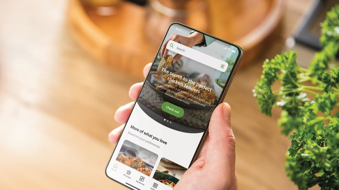 Hand holding a smartphone displaying a recipe app with chicken tenders