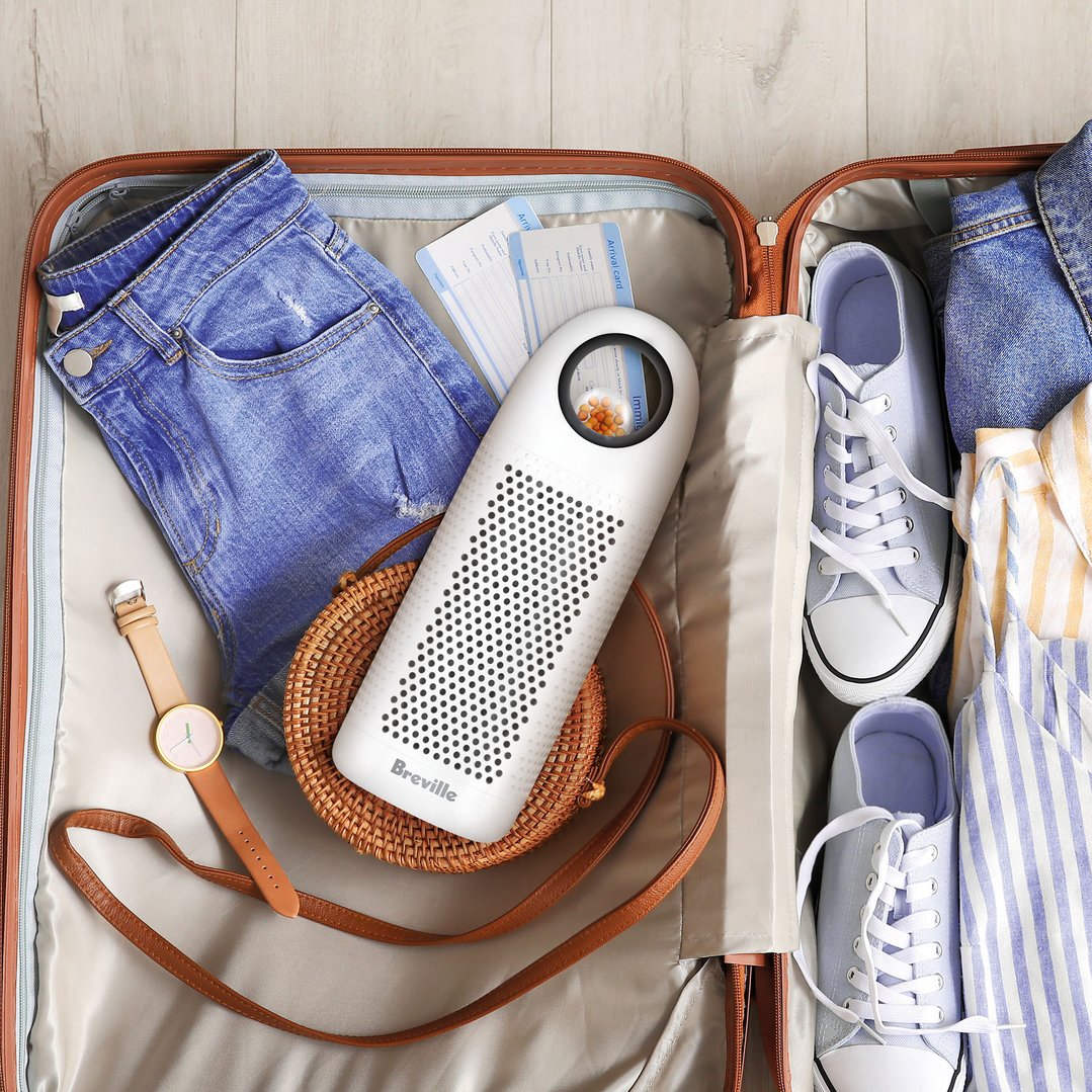Breville dehumidifier in an open suitcase with clothes, shoes, and accessories
