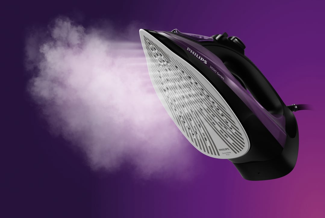 Philips 5000 Series steam iron releasing steam against a purple background