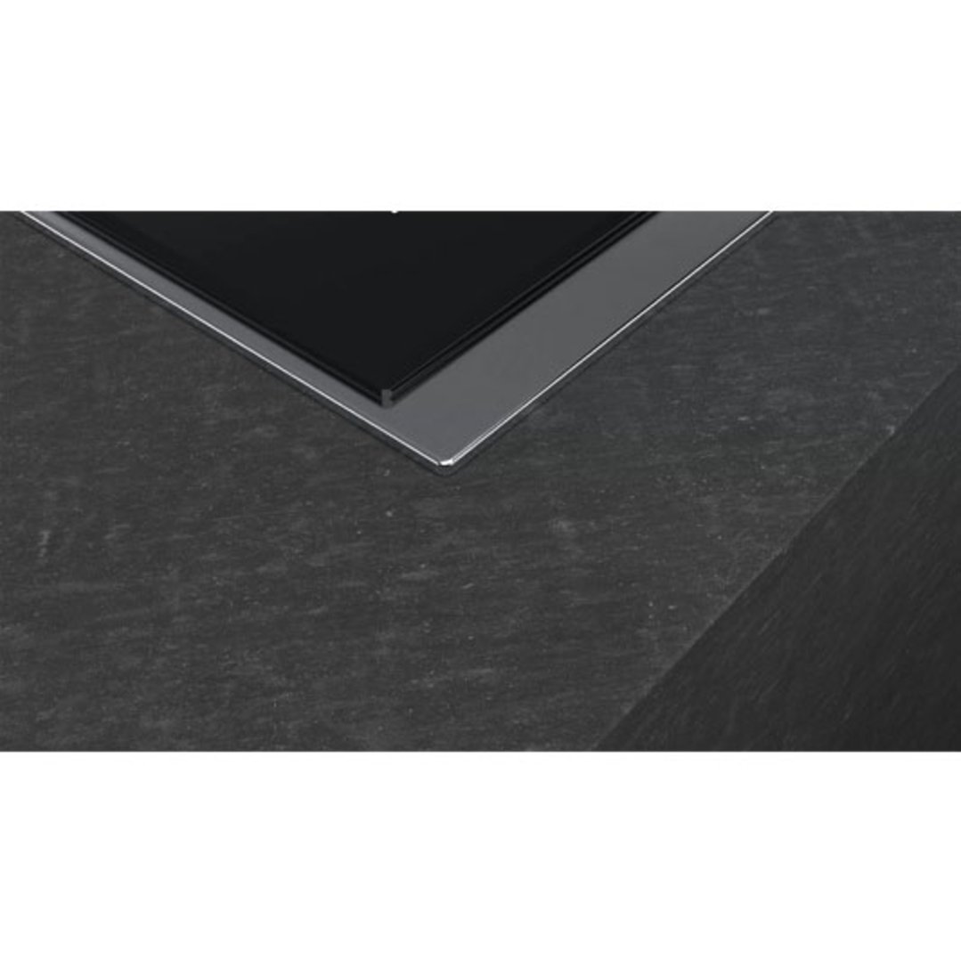 Close up of a black cooktop integrated into a dark stone countertop
