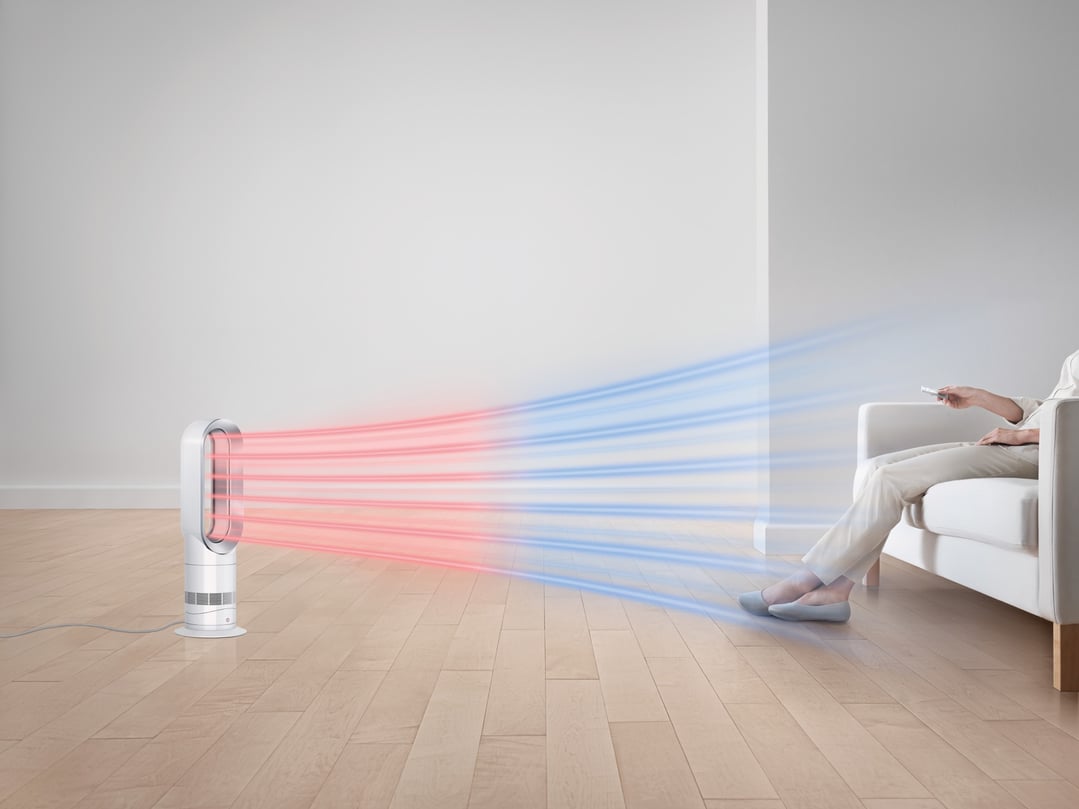 Dyson Hot+Cool fan heater projecting hot and cool air towards a person on a sofa