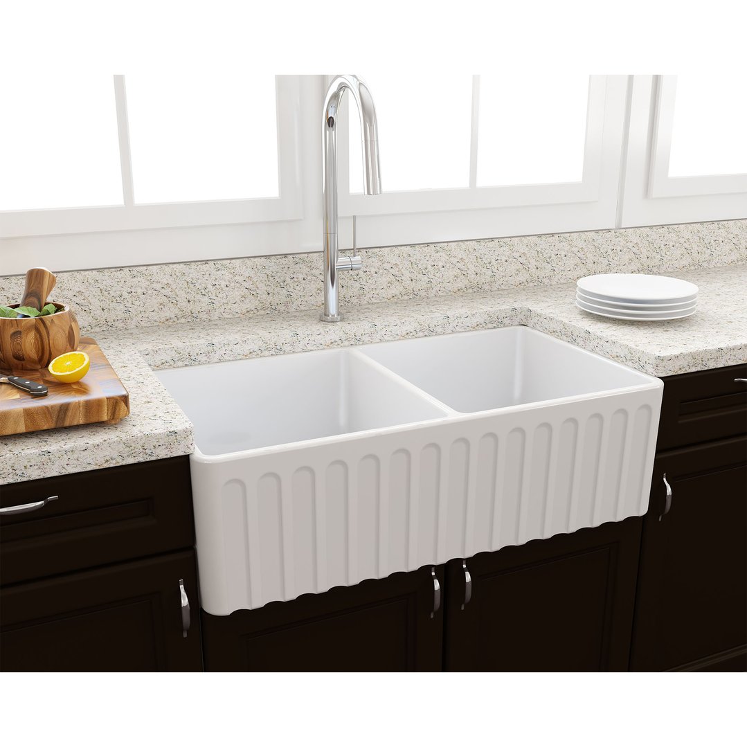 White double bowl fireclay sink in a kitchen with a cutting board and lemon