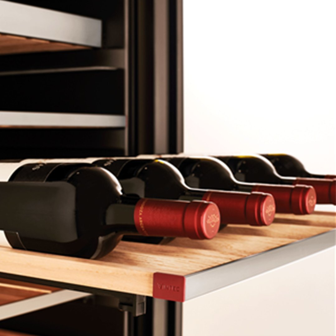 Close up of red wine bottles on wooden shelves inside a wine cabinet