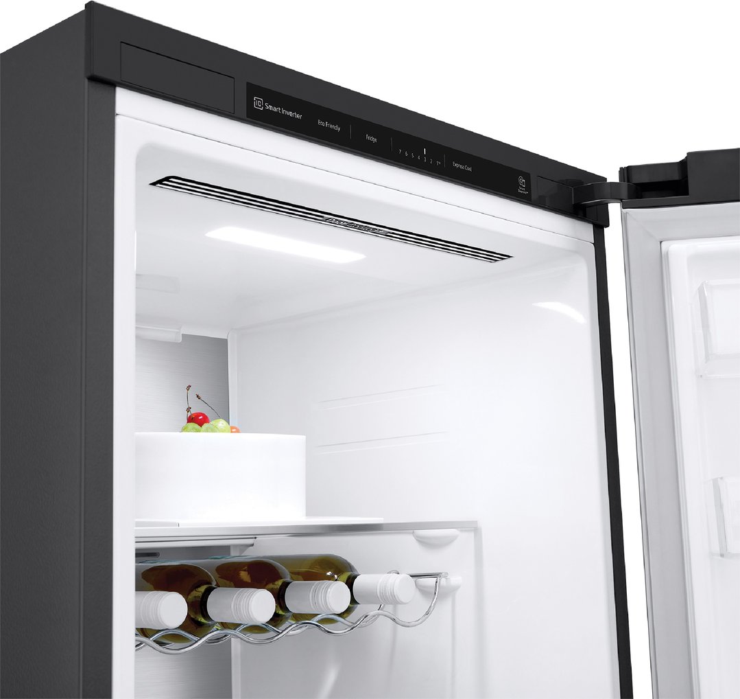 Open matte black single door fridge interior with wine bottles and cake
