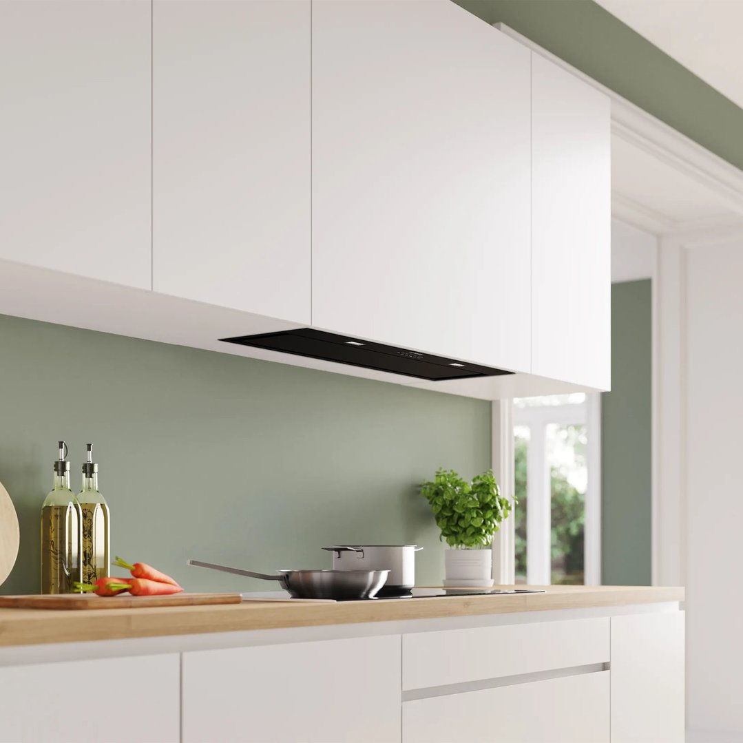 Integrated rangehood in a modern kitchen with white cabinets and green walls