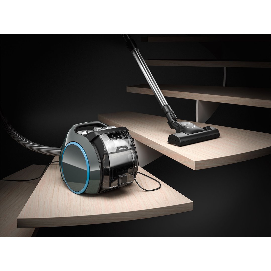 Miele Boost CX1 vacuum cleaner on wooden stairs with vacuum head on upper step