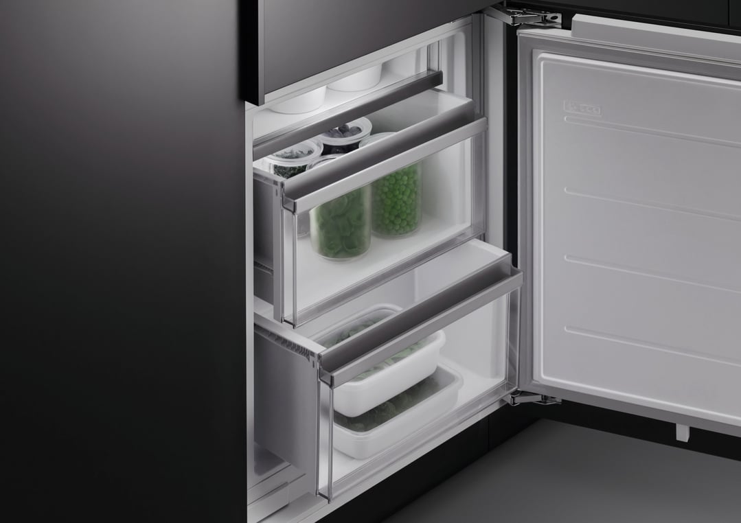 Open integrated refrigerator freezer showing frozen food in drawers