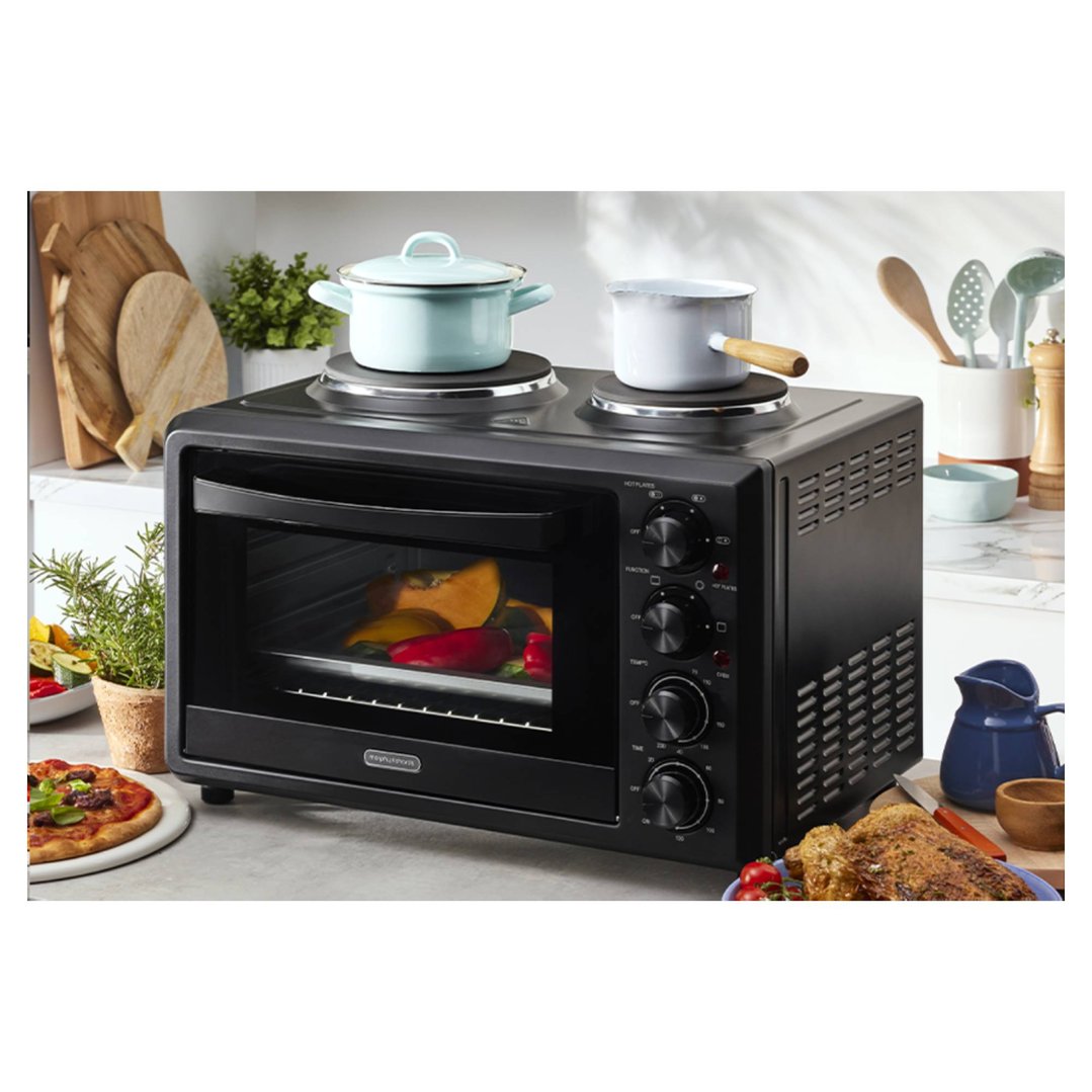 Black convection oven with hot plates cooking food in a kitchen setting