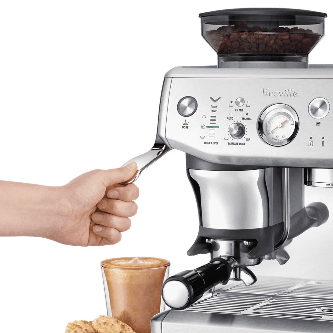 Hand pulling lever on Breville coffee machine with coffee and cookies