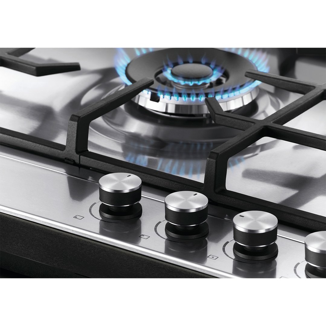 Close up of a gas cooktop with one burner lit and control knobs