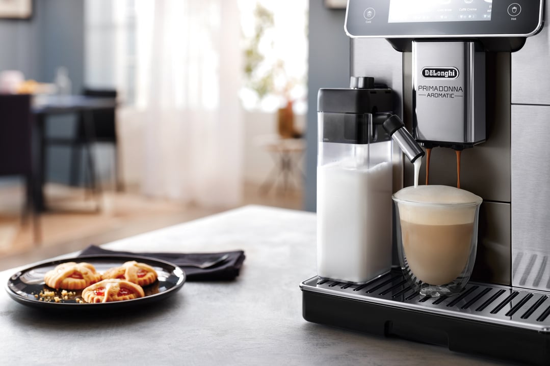 DeLonghi Prima Donna Aromatic fully automatic coffee machine making a latte with cookies
