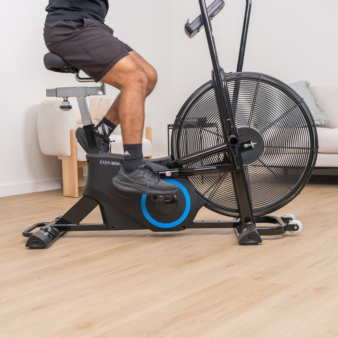 Person exercising on a black exercise bike in a light-filled room