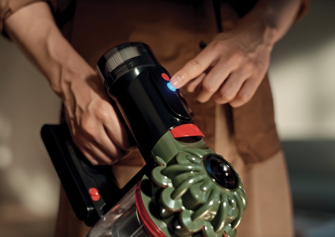 Person's hands operating a Dyson V8 Cyclone handstick vacuum cleaner