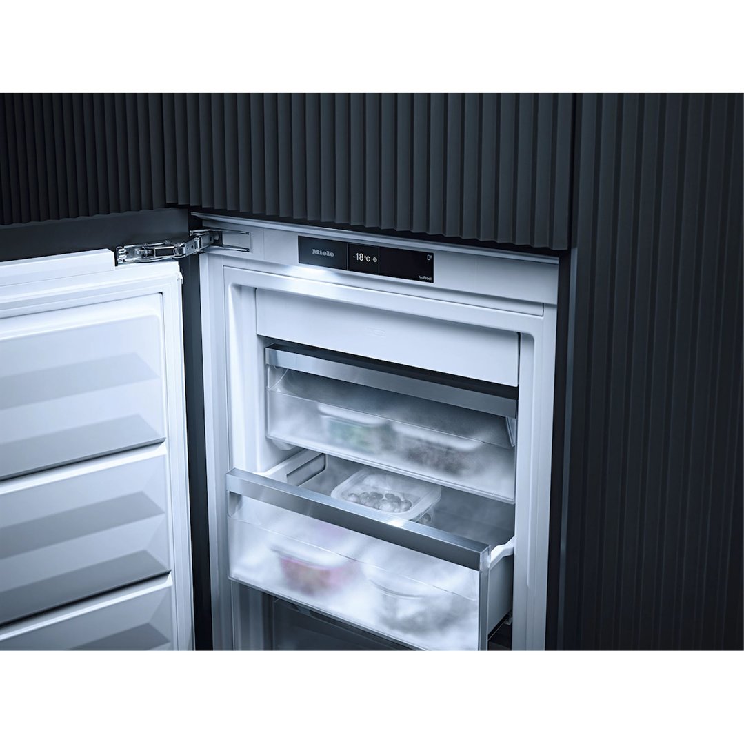 Open integrated freezer showing interior drawers with food items and digital display