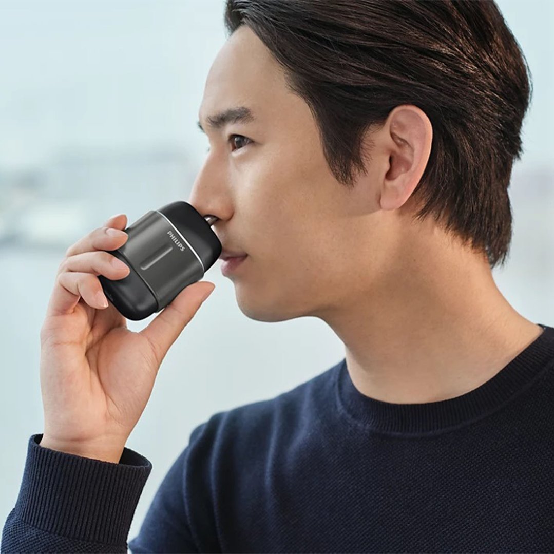 Man using a Philips electric shaver to trim nose hair