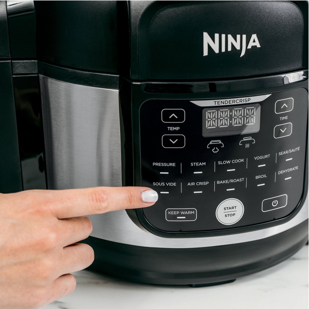 A hand presses a button on the control panel of a Ninja multi cooker