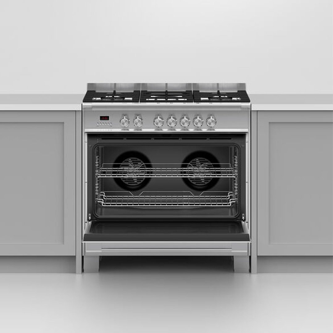 Stainless steel dual fuel cooker with oven door open in a kitchen setting