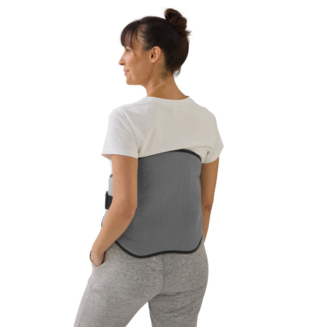 Woman wearing a grey lower back heating pad over a white t-shirt